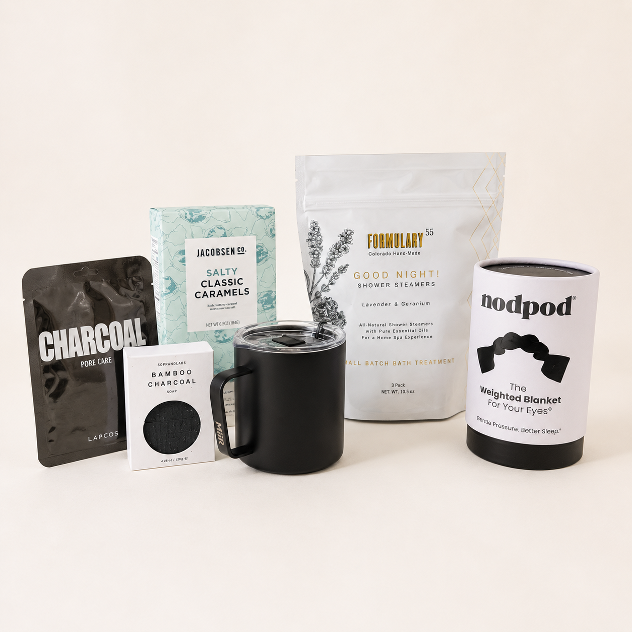 Collection of products including a mug, packages, and a blanket on a light background