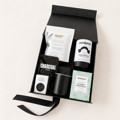 Gift set with various items including a black mug, charcoal product, and other packaged goods on a white background.