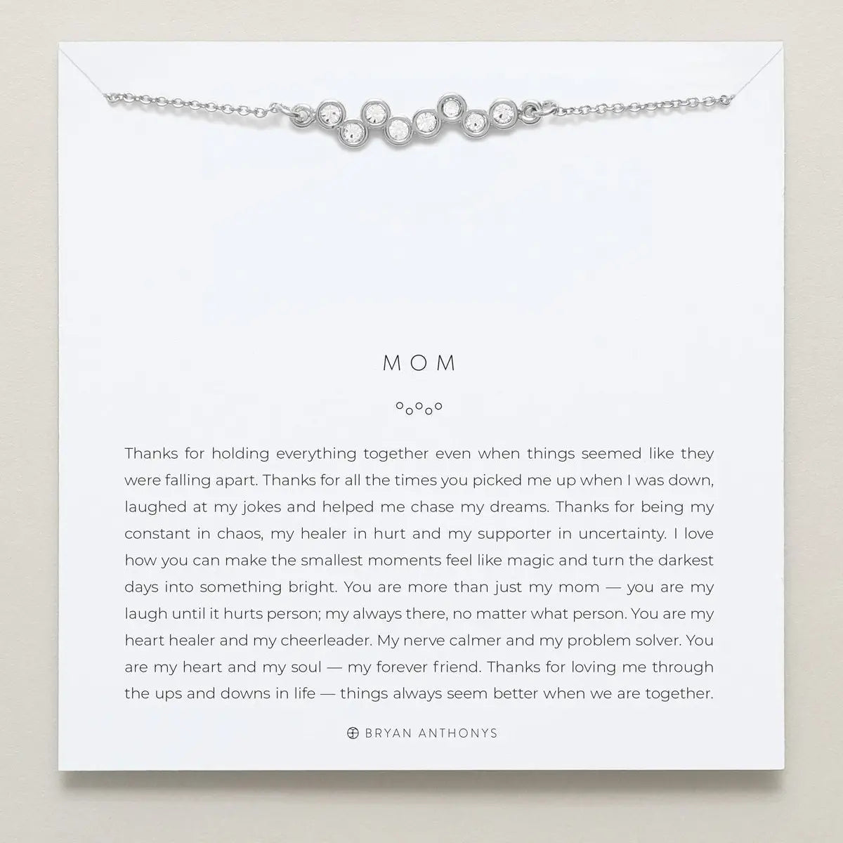 Silver necklace on a card with a message for 'Mom' on a beige background