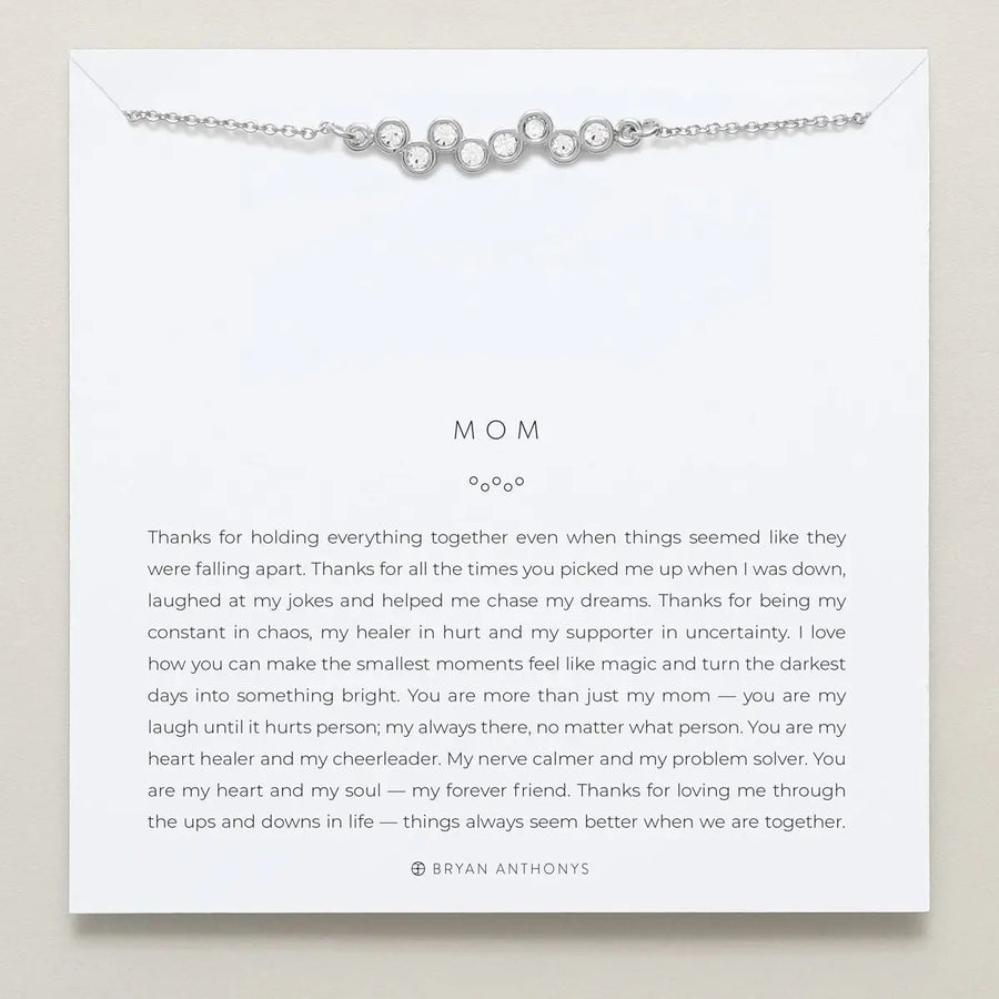 Silver necklace on a card with a message for 'Mom' on a beige background