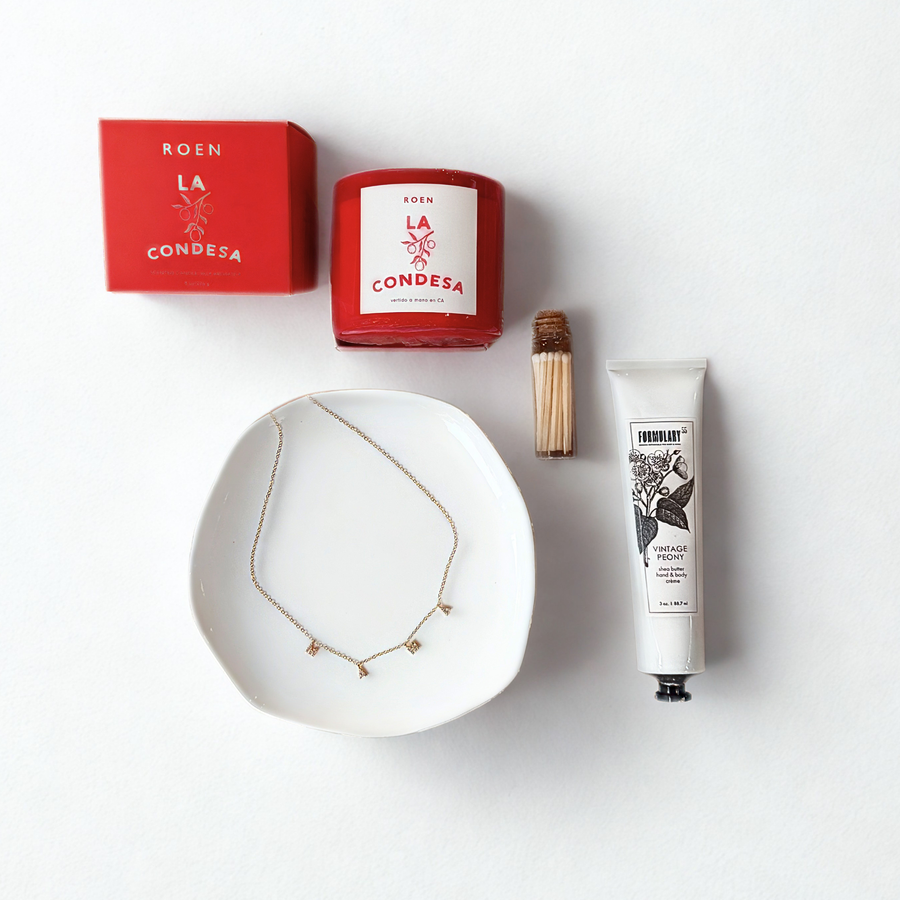 Collection of beauty products including a candle, necklace, and tube on a white background