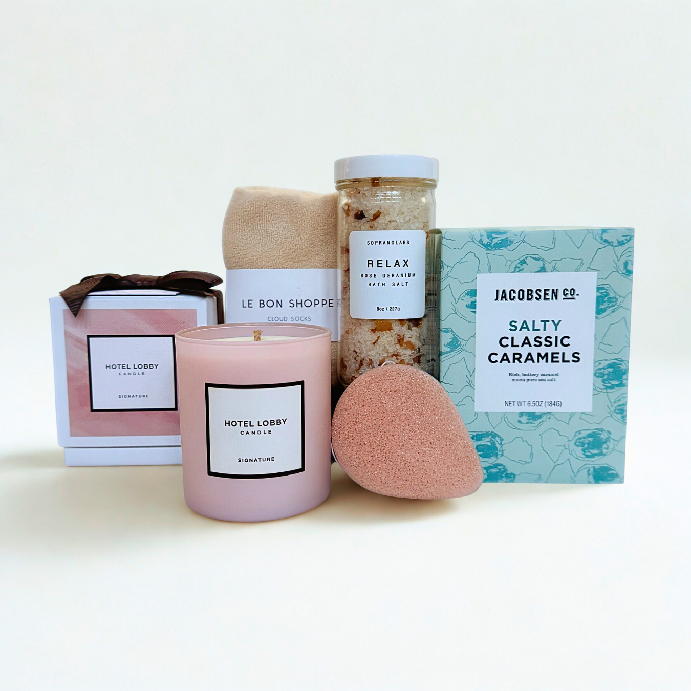 Collection of items including a candle, bath bombs, and a box of caramels on a white background