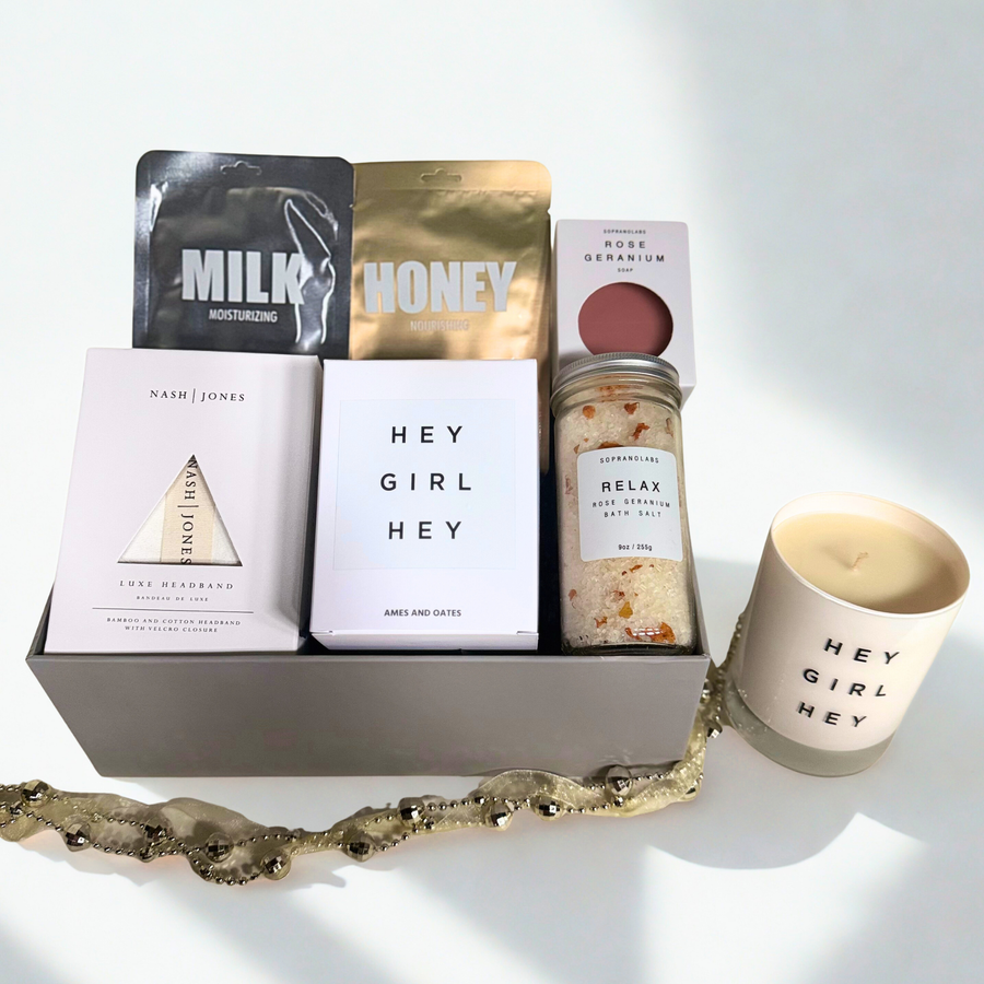 Gifting set with candles, bath salts, and other self-care items on a white background