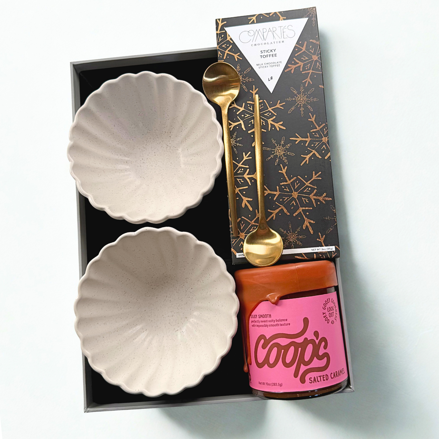 Set of two ceramic bowls, a gold spoon, and a pink canister labeled 'Coop's' in a gift box.
