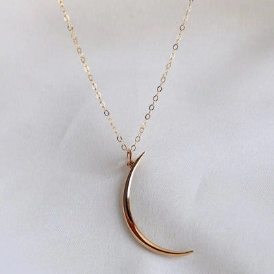 Gold crescent moon necklace on white background
