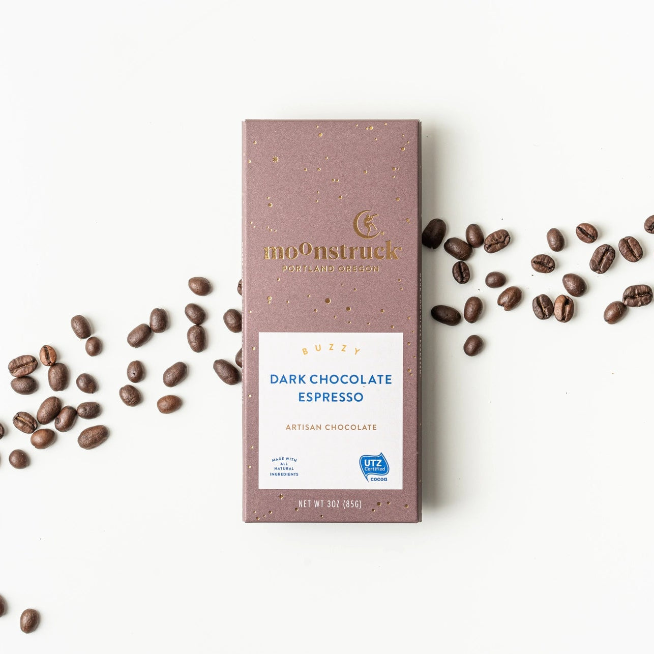 Moonstruck Dark Chocolate Espresso bar with scattered coffee beans on a white background