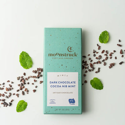 Moonstruck minty dark chocolate cocoa nib mint packaging with cocoa nibs and mint leaves on a white background