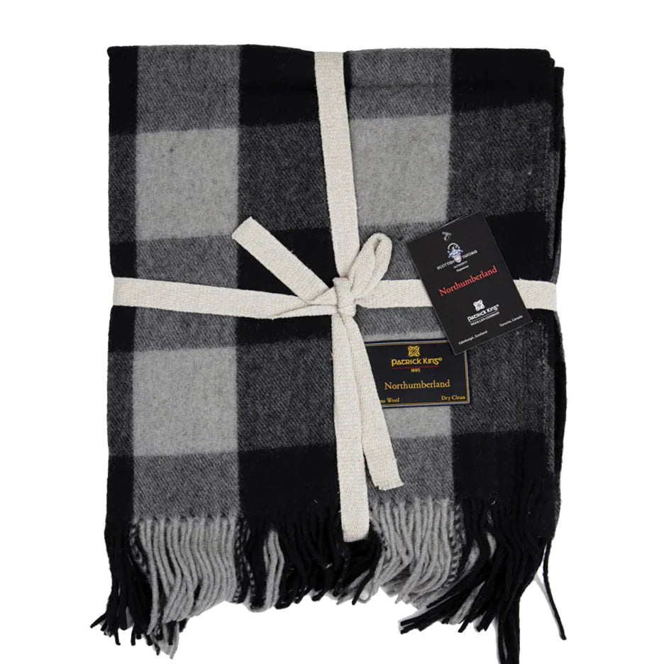 Plaid blanket with black and gray pattern, tied with a white ribbon, on a white background.