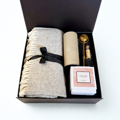 Gift set with a blanket, candle, and other items in a box on a white background