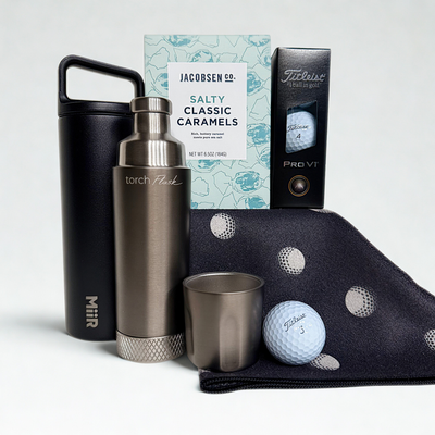 Golf-themed gift set with torch flask, golf ball, and caramels on a white background