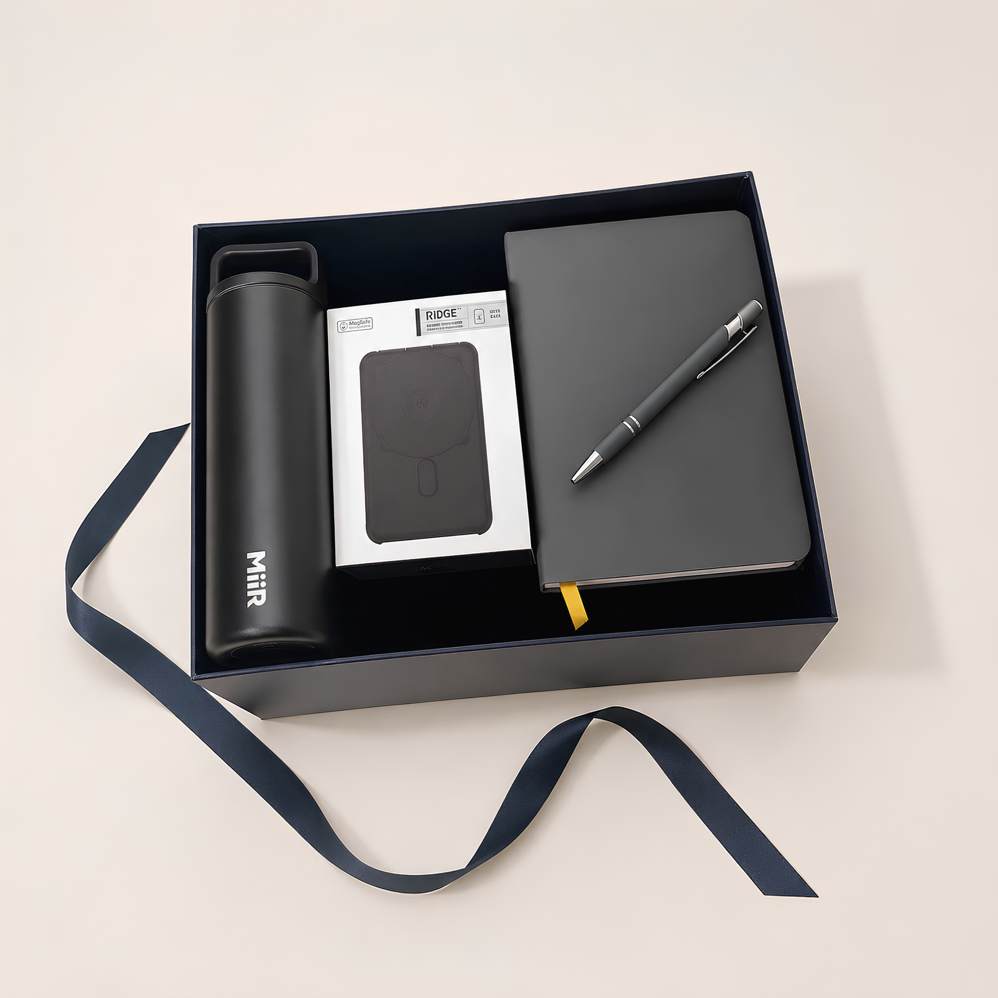 Gift set with black water bottle, Ridge powerbank, notebook, and pen in a box on a light background