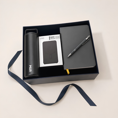Gift set with black water bottle, Ridge powerbank, notebook, and pen in a box on a light background